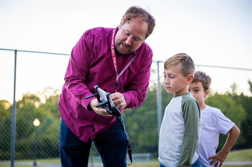 A teacher helps a boy use a drone